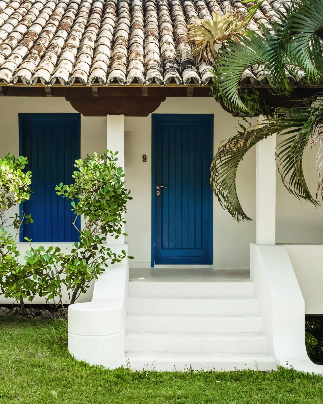 Entrada de suíte Vila com portas azuis e jardim